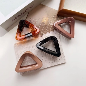 Detail of four triangle hair claws in tortoiseshell and neutral colors on stone decor