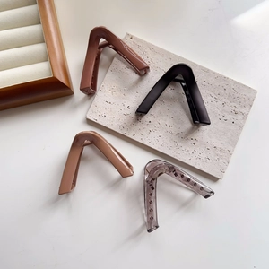 Detail of four V-shaped hair claws in coffee, black, beige, and grey finishes