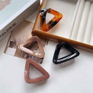 Close-up of four geometric triangle hair claw clips in amber, black, coffee, and pink