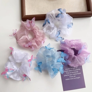 Détail de chouchous en organza avec breloques papillon 3D et strass brillants décoratifs