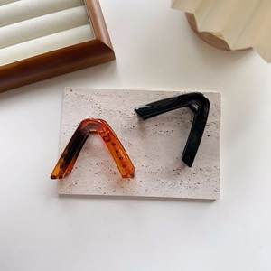 Close-up of V-shaped large hair claw clips in tortoiseshell and glossy black resin