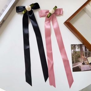 Detailed view of satin ribbon bow hair clips with white roses in black and pink colors