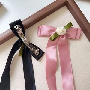 Detail of silk satin bow hair clips with rose accents and metal alligator clip