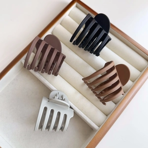 Lot de quatre pinces à cheveux mates en noir, marron et beige sur un présentoir blanc