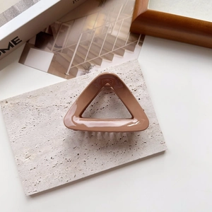 Macro view of coffee brown triangular hair claw clip with glossy finish and metal spring