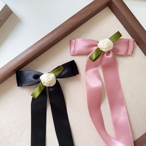 Detailed shot of black and pink satin ribbon bow hair clips with rose accents