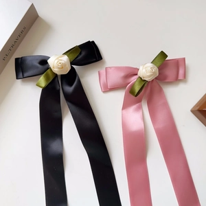 Detail of satin bow hair clips with rose decor and long ribbons in pink and black