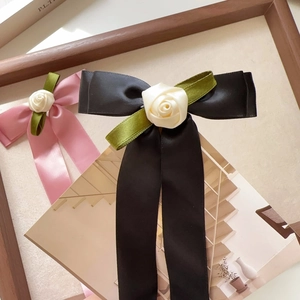 Detail of satin bow hair clips with fabric roses and elegant long ribbon streamers