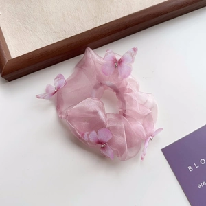 Détail d'un chouchou en organza rose avec papillons 3D et petits strass brillants