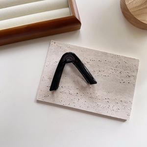 Macro detail of glossy black V-shaped hair claw clip with a secure metal spring mechanism