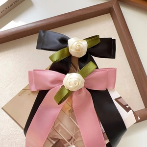 Detail of pink and black satin hair clips featuring cloth rose and green ribbon leaves