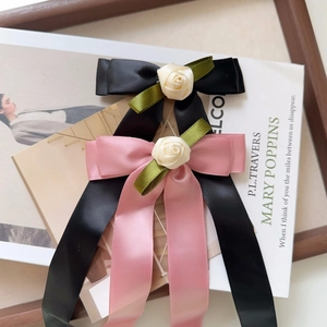 Close-up of satin bow hair clips with textile roses and long elegant ribbons