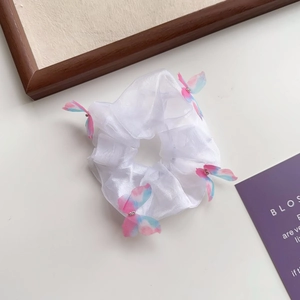 Détail d'un chouchou en organza blanc avec des breloques papillon roses et bleues