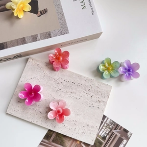 Close-up of colorful resin flower hair claws on a textured stone and book background
