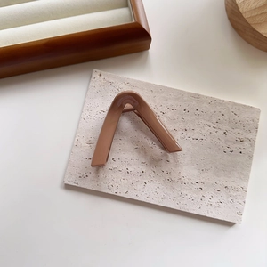 Detail view of a minimalist V-shaped hair claw clip in glossy brown resin on stone surface