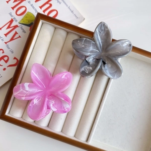 Dettaglio delle pinze per capelli a fiore effetto marmo in un vassoio portagioie elegante