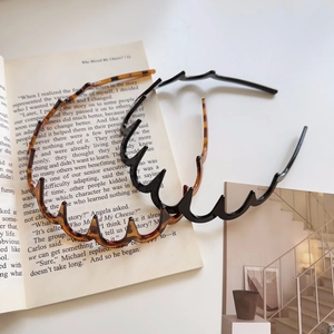 Close-up of zigzag wave headbands in classic black and tortoise shell patterns on a book