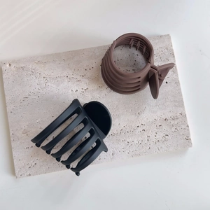 Détails de pinces à cheveux mates noires et café sur un plateau en pierre neutre