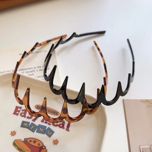Close-up of wavy toothed headbands in tortoise shell and black on a white ceramic plate