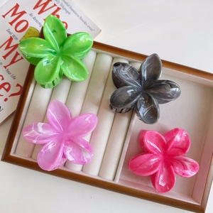 Dettaglio di quattro mollette per capelli a fiore colorate con trama marmorizzata