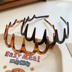 Detail of wavy hair hoops with teeth in leopard print and classic black resin finish