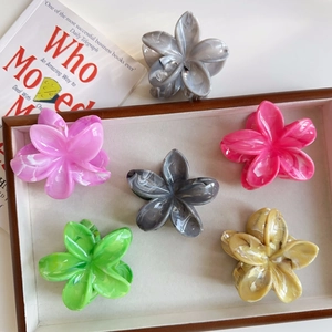 Dettaglio di fermagli per capelli a forma di fiore effetto marmo su vassoio in legno