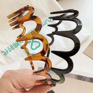 Detail showing wavy zig-zag hairbands in glossy black and tortoise shell resin finish