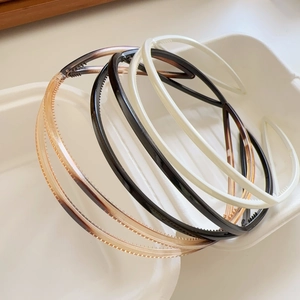 Detail of multi-colored slim hairbands with non-slip teeth in a white container