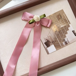 Detail view of pink satin bow hair clip with fabric rose and long flowing ribbons