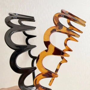 Detail view of wavy zig-zag headbands in glossy black and classic tortoiseshell resin