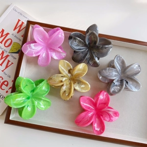 Dettaglio di pinze per capelli a fiore in sei colori con texture marmorizzata su vassoio