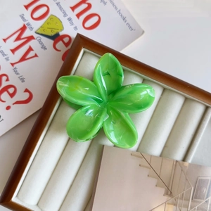 Dettaglio di un fermaglio per capelli a fiore verde lucido in acetato su vassoio