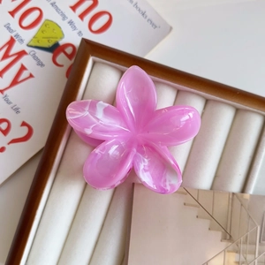 Dettaglio molletta per capelli a fiore marmorizzato rosa e bianco su vassoio