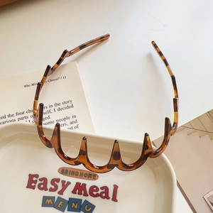 Detail of a wavy tortoiseshell headband with comb teeth on a ceramic tray display