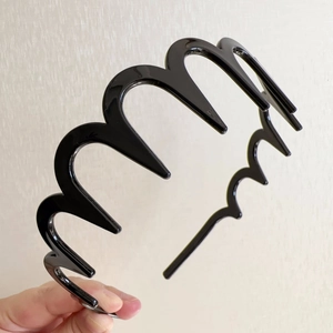 Close-up of black wavy toothed headband made of high-shine plastic with firm hair grip