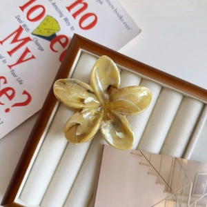 Dettaglio del fermaglio per capelli a fiore ambra con trama marmorea su base bianca
