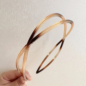 Close-up of tortoiseshell double cross headband with anti-slip inner teeth for secure grip