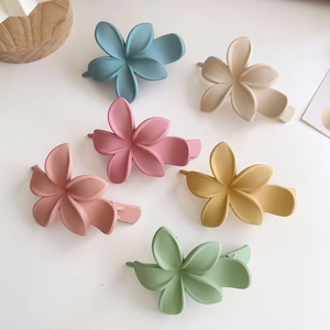 Vue à plat de six pinces à cheveux fleurs mates aux couleurs Morandi sur fond blanc