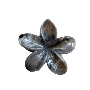 Elegante pinza per capelli a fiore con trama marmorizzata bianca e nera su sfondo bianco