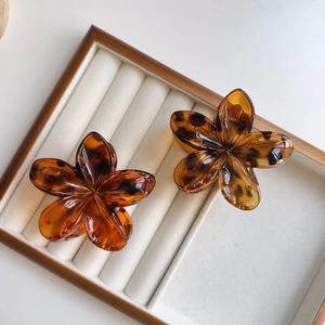 Dettaglio di fermacapelli a fiori in tartaruga su un vassoio per gioielli bianco