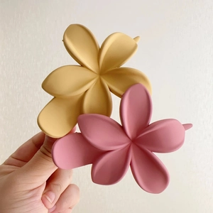 Détail de pinces à cheveux fleurs mates en résine jaune gingembre et rose clair