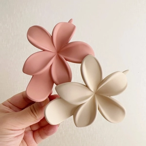 Détail de deux pinces à cheveux fleurs mates en rose et beige pour les coiffures d'été