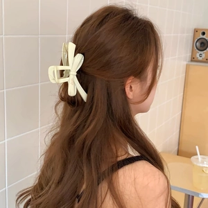 Macro detail of a cream ribbon bow hair claw clip worn on a elegant updo hairstyle