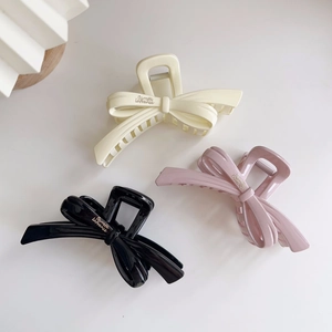 Elegant bow hair claws in cream, pink, and black colors with glossy resin finish