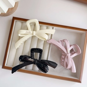 Detailed close-up of ribbon bow hair claws in cream, black, and pink resin finish