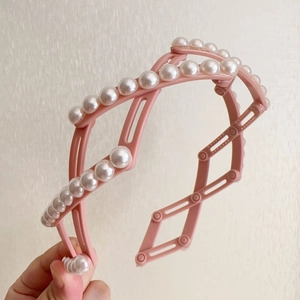 Détail du serre-tête pliable rose avec perles blanches pour un rangement de voyage compact
