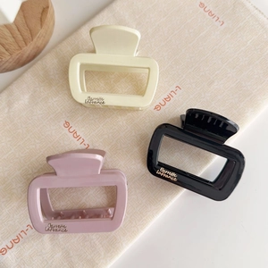 Vue détaillée de pinces à cheveux carrées en beige, noir et rose avec logo de marque