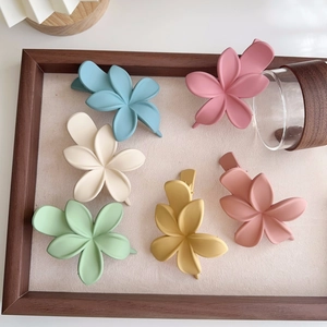Détail de pinces à cheveux fleur mat en six couleurs pastel disposées sur un plateau