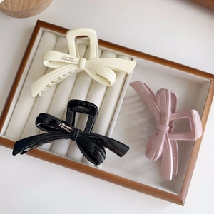 Detailed set of bow-shaped resin hair claws in creamy white, classic black, and light pink