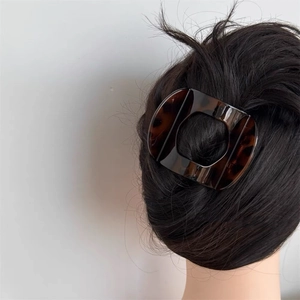 Detail view of large tortoiseshell hair claw clip holding a hairstyle on curly hair